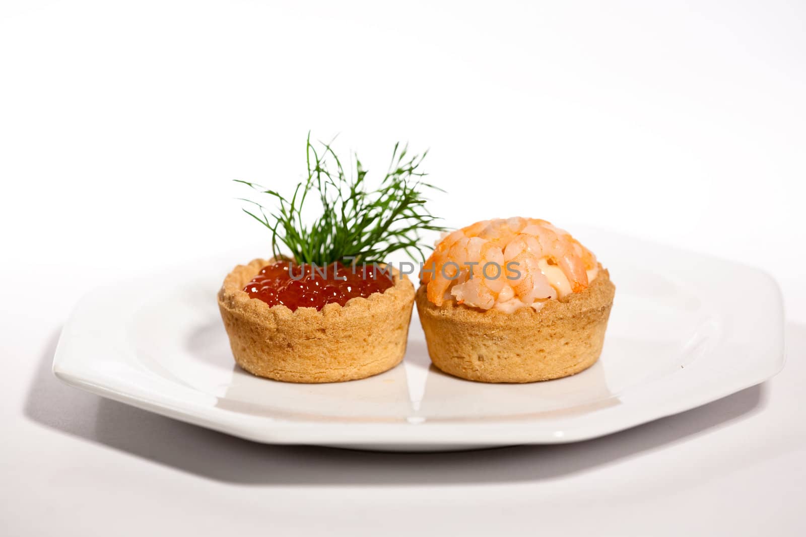 two canapes with caviar and shrimp on white
