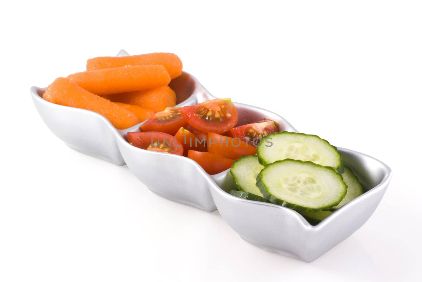 Silver colored bowl with three compartments filled with three kinds of vegetables, isolated on white.