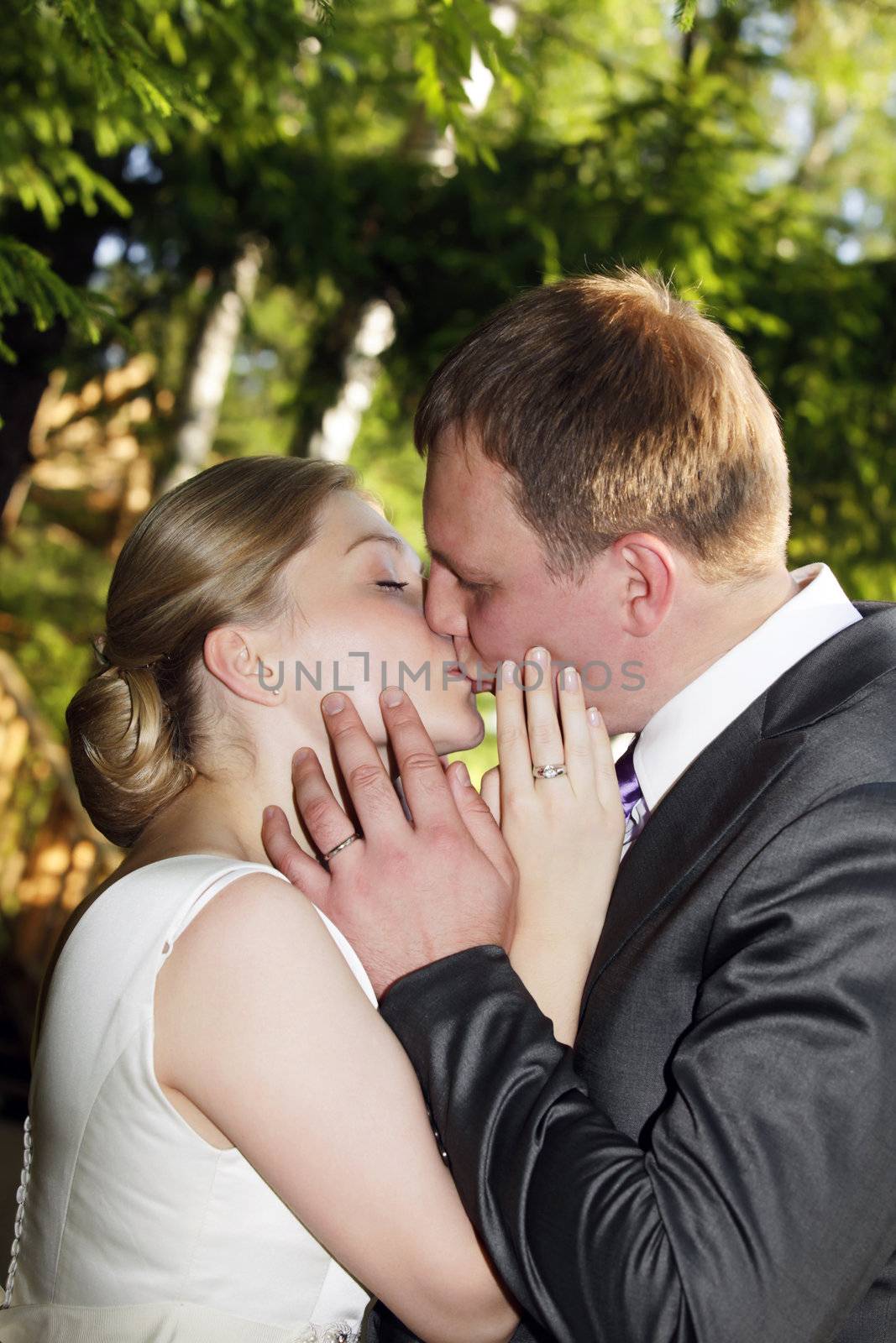 The groom and the bride kiss in park