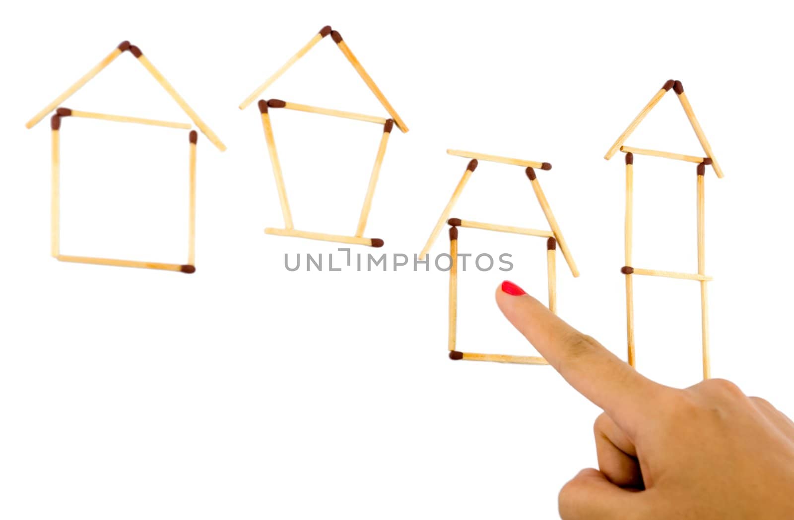 woman index finger pointing to one of several housing model made from matches isolated on white