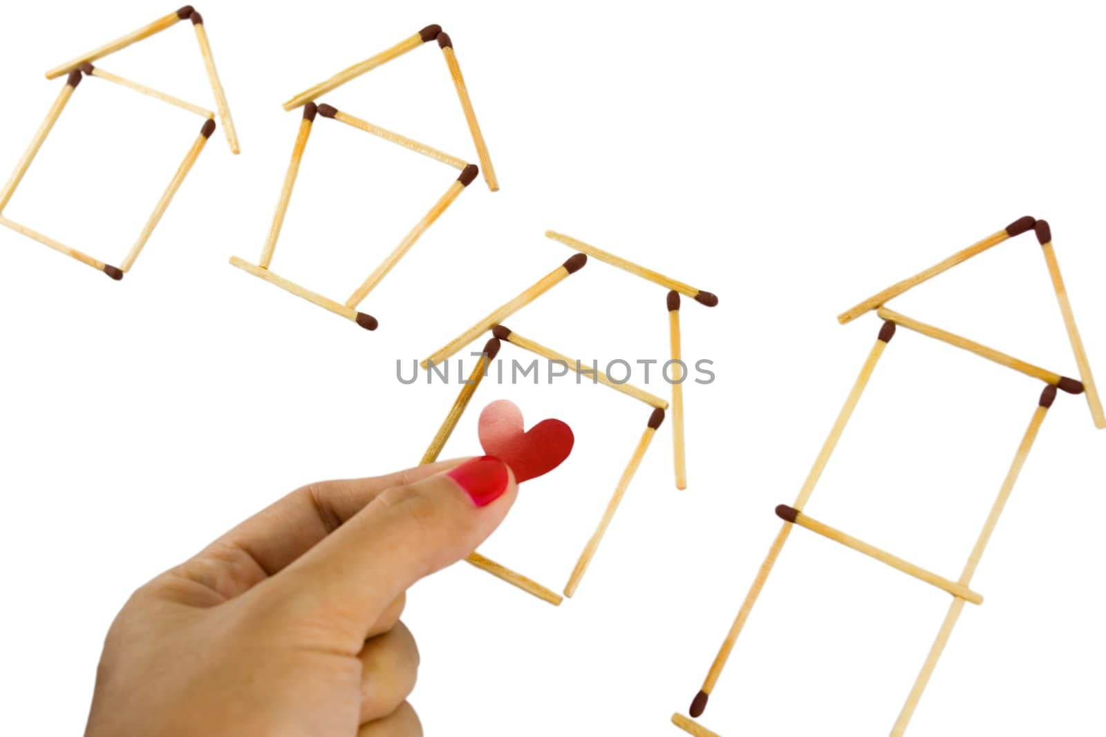 woman fingers tagging one of several housing model made from matches isolated on white