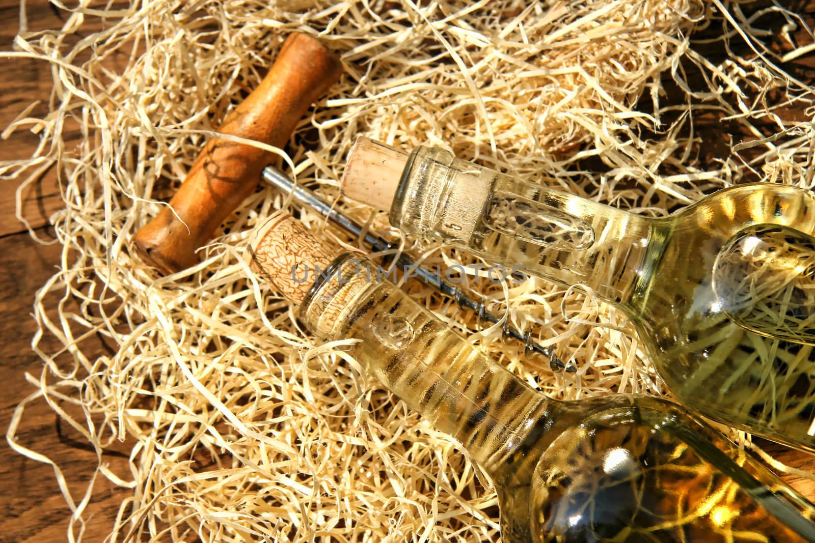 Bottles of wine laying on packing straw with cork screw