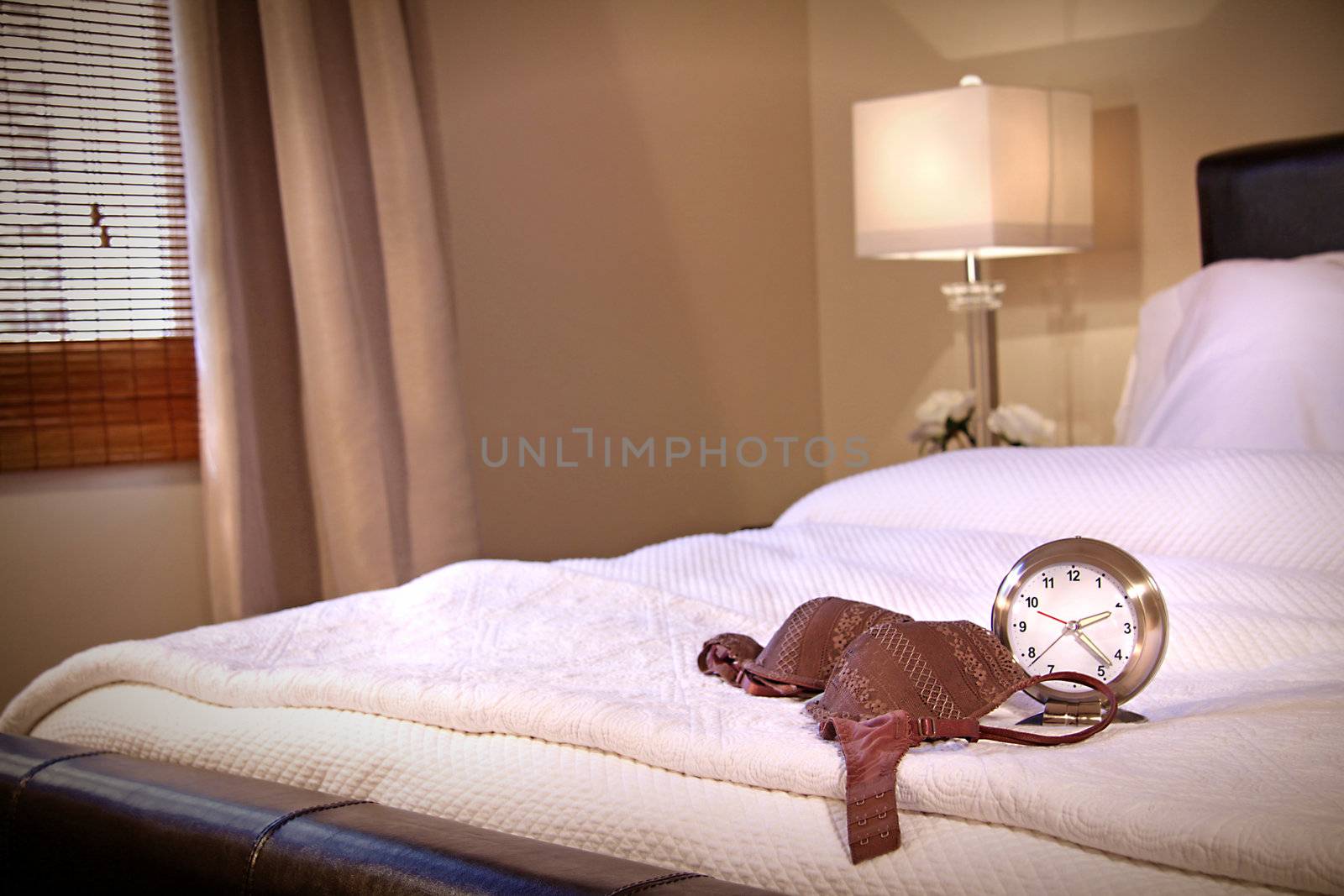 Lace brassiere laying across bed with clock