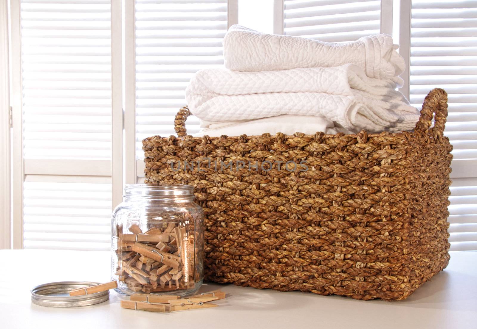 Laundry basket with linens on table with clothespins in jar