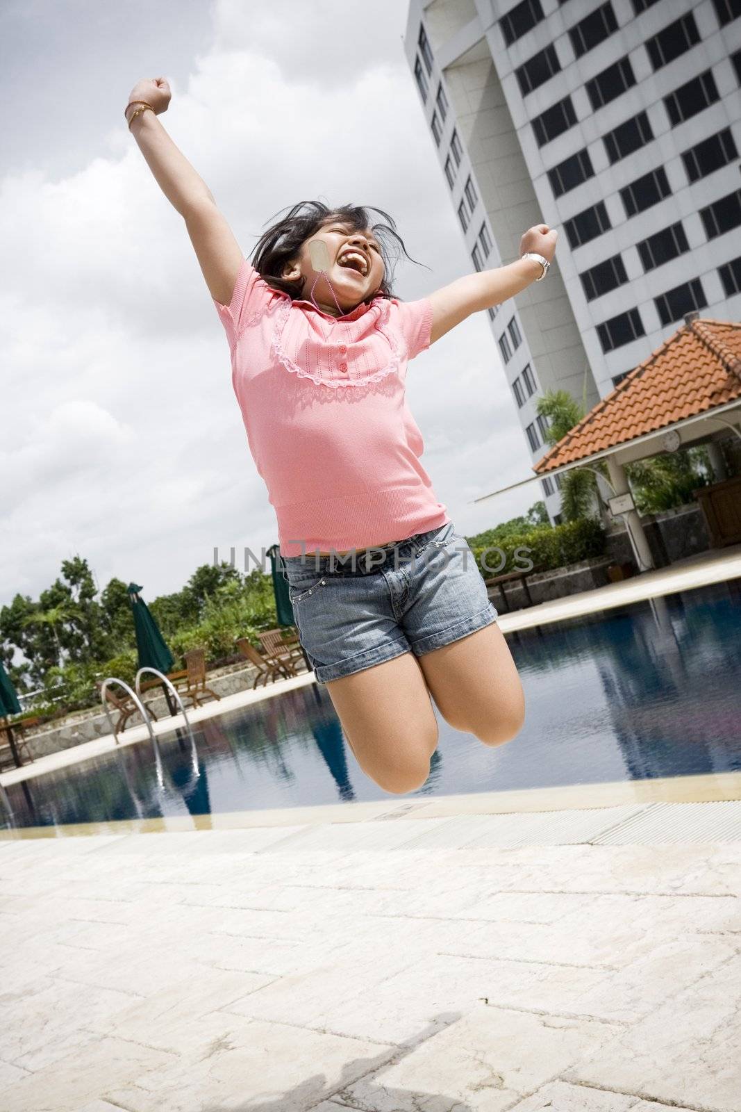 conceptual portrait of asian little girl jumping by the pool, excited on having a great vacation 