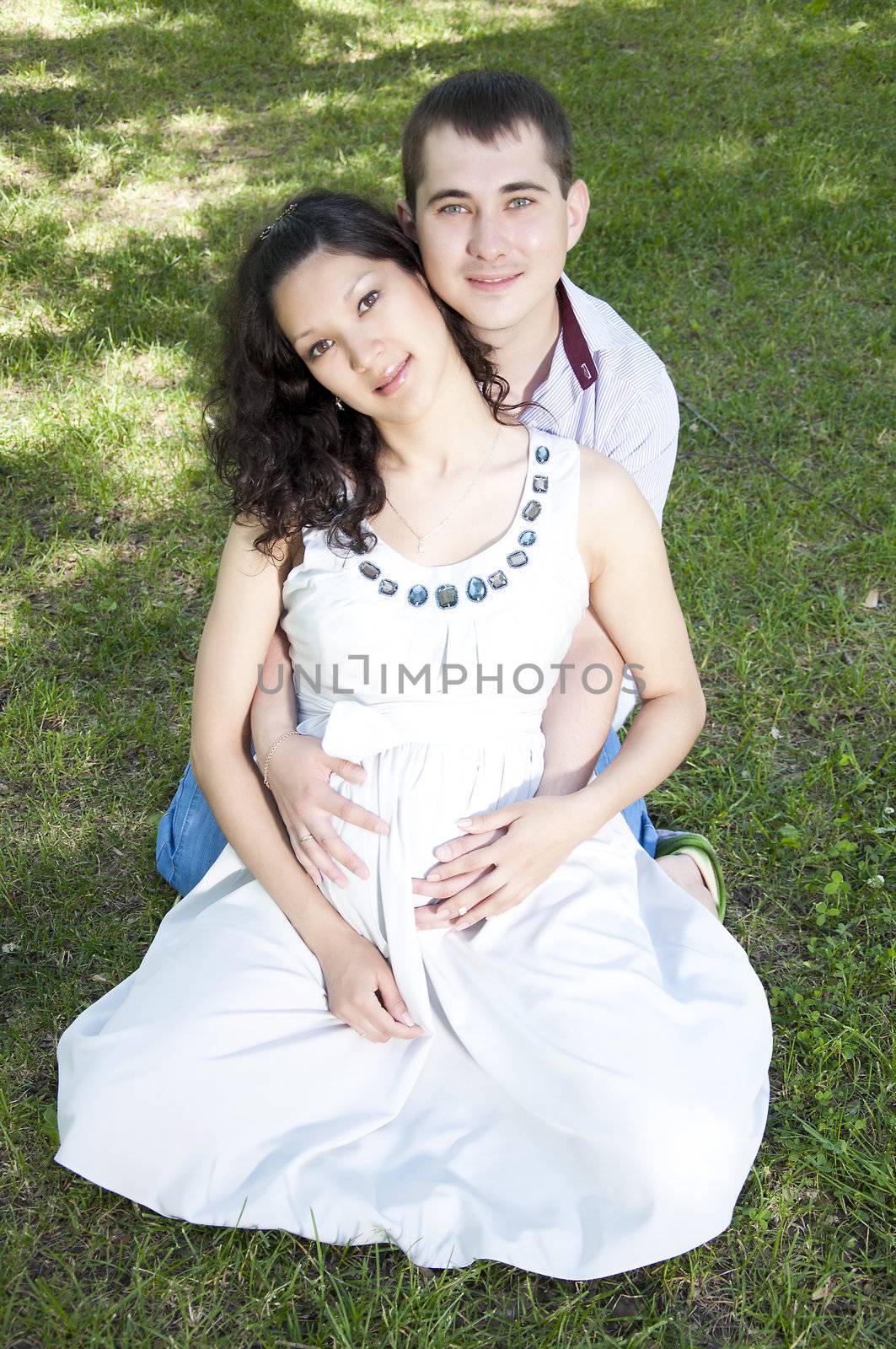 Man and pregnant woman hugging in park by adam121