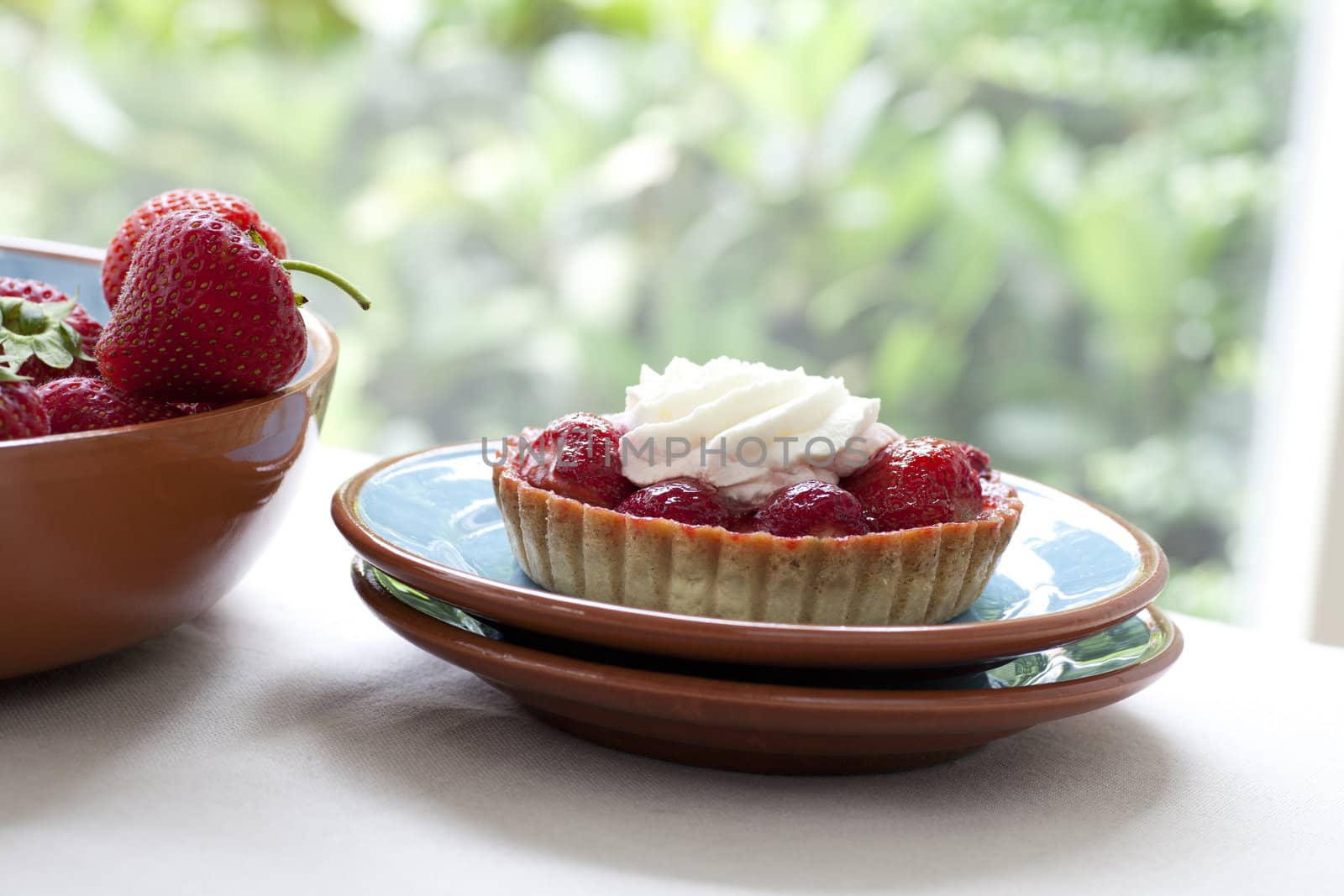 Strawberry tart topped with whipped cream.