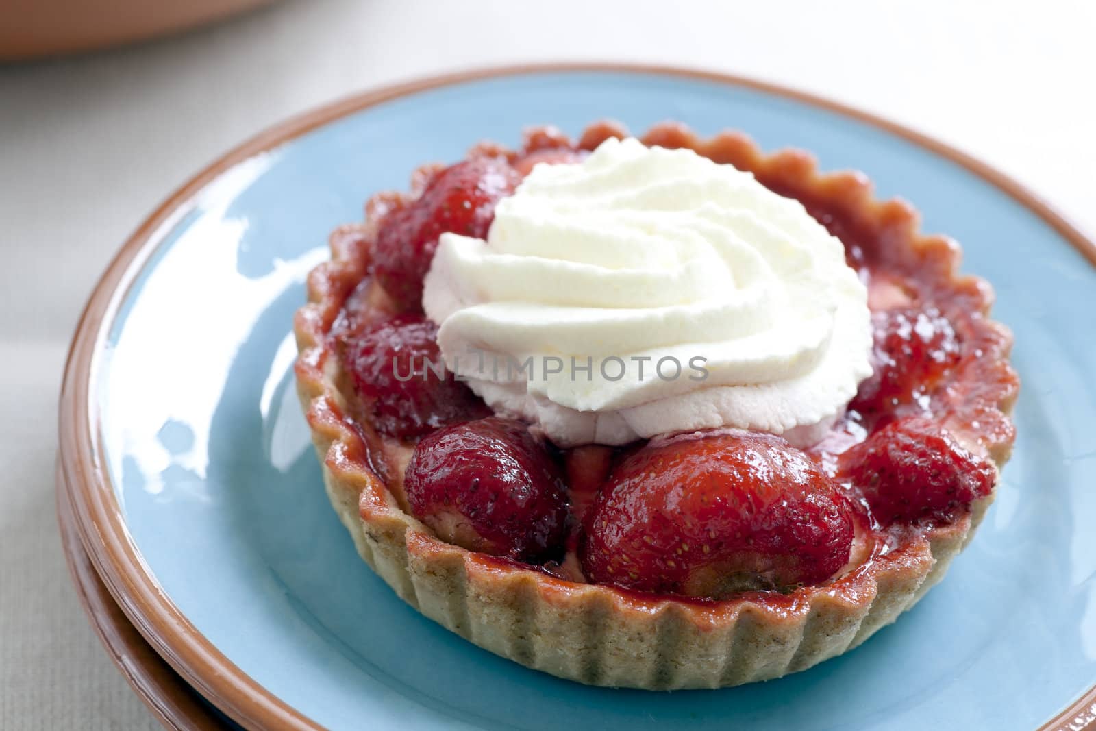Strawberry tart topped with whipped cream.