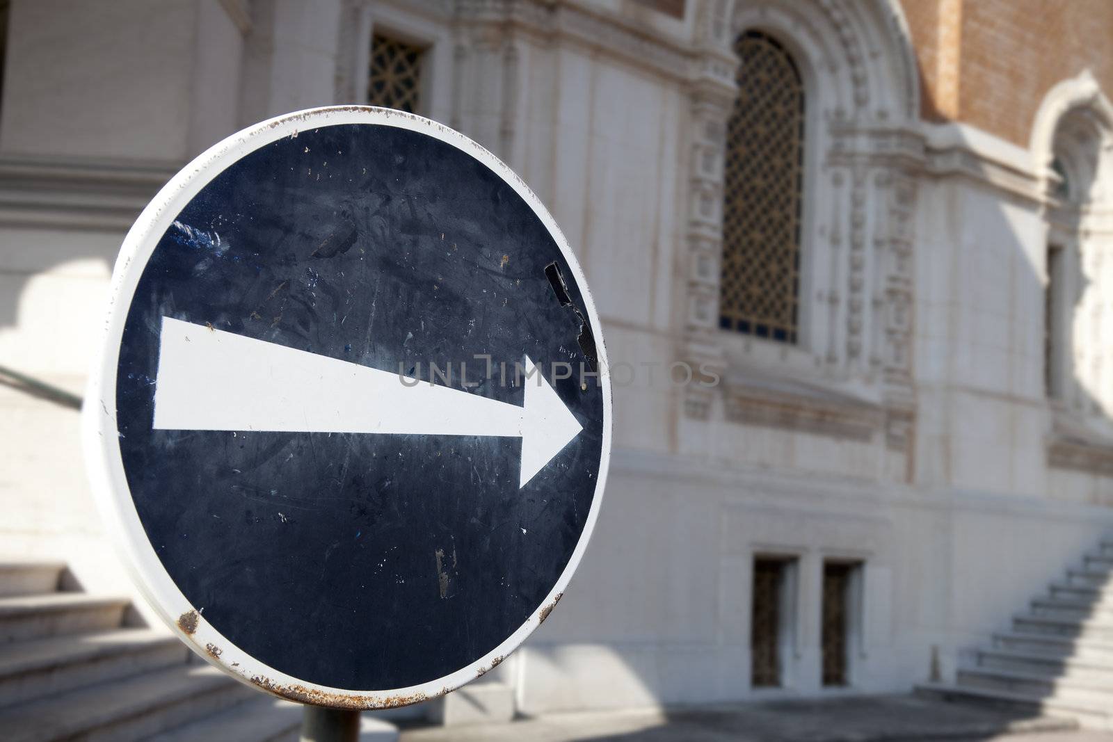 Grungy sign with white arrow pointing to the right.