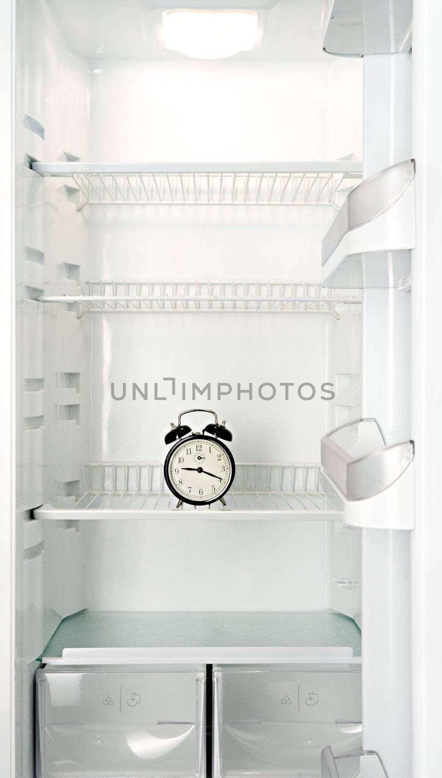 Round alarm clock in an empty refrigerator
