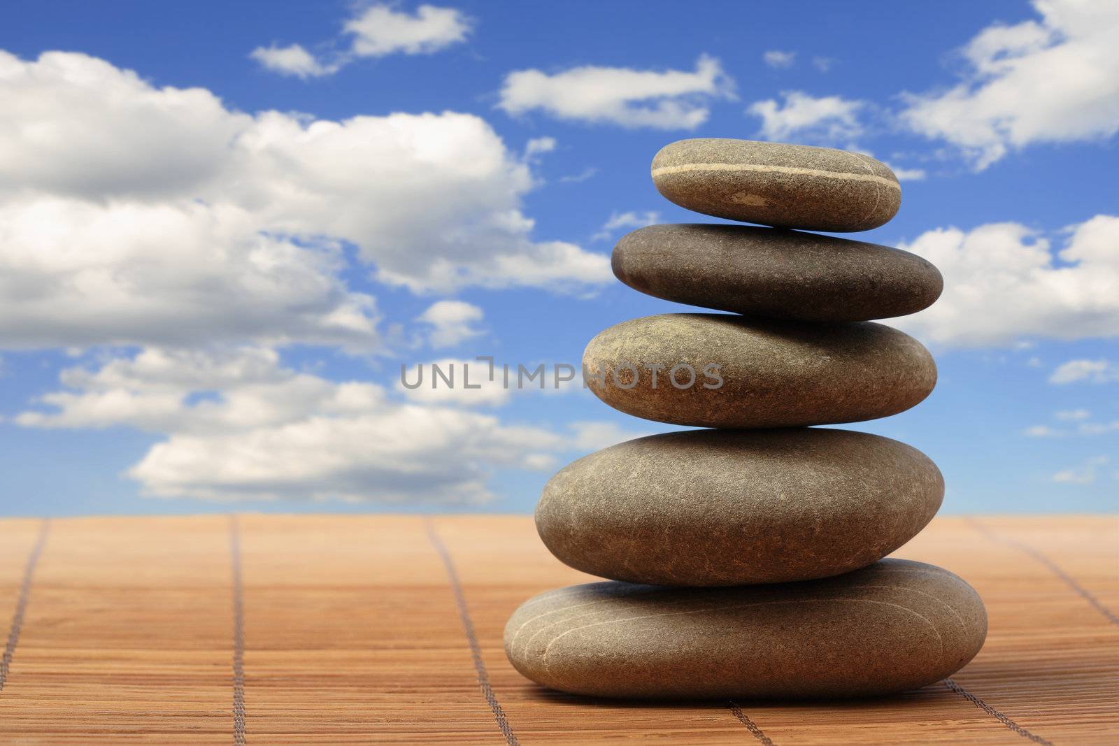 Pyramid from five smooth round grey stones on a heavenly background
