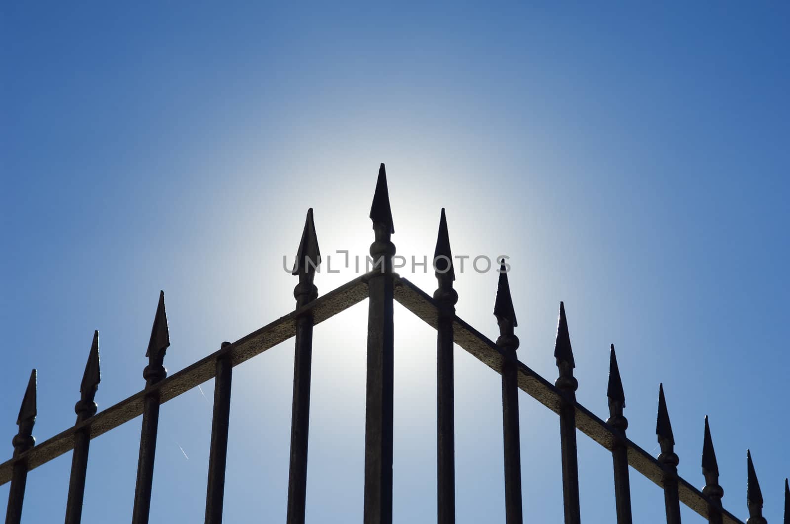Edge of an old spiked iron railing against the shinning sun.