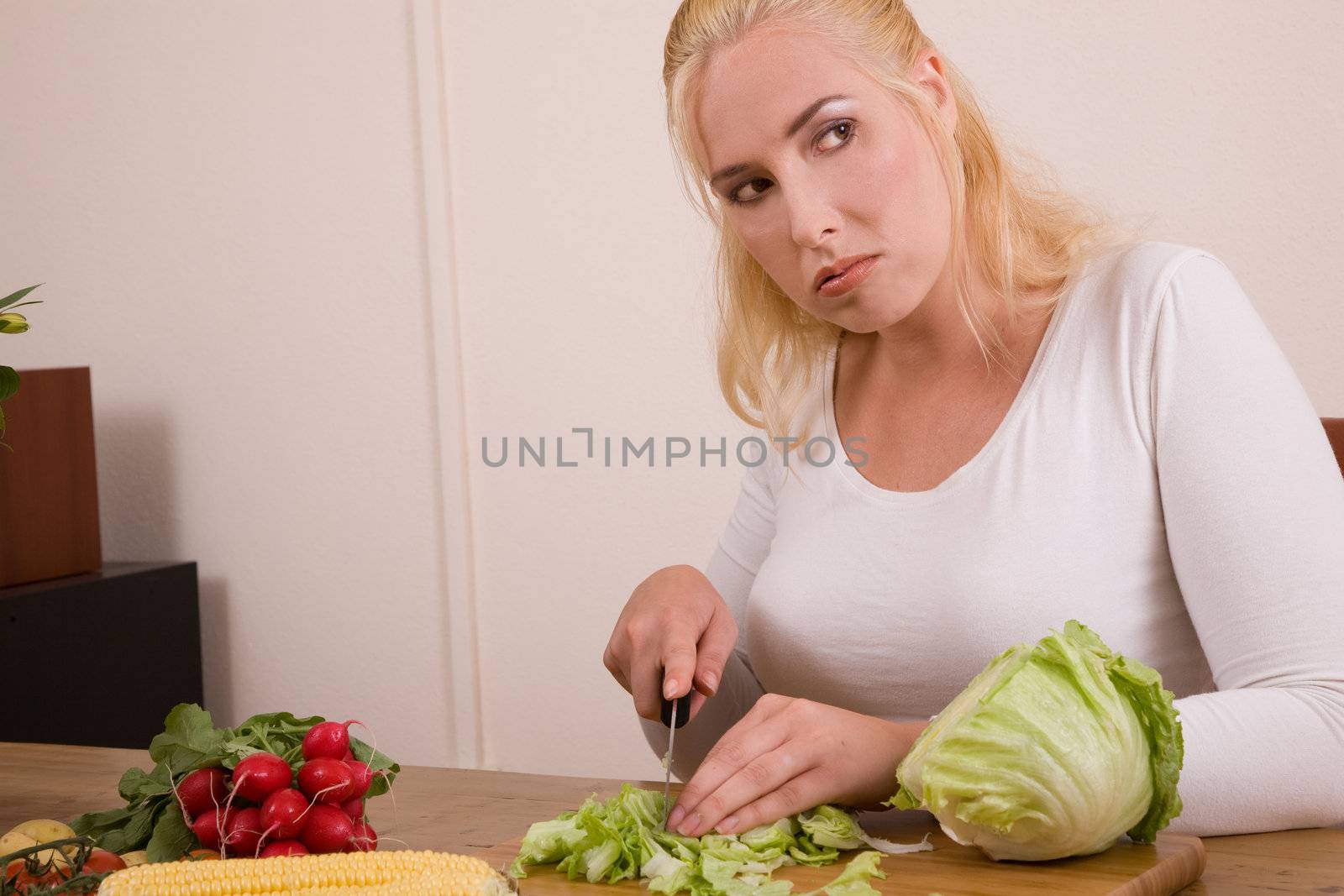 pretty blond housewife looking very bored working in the kitchen