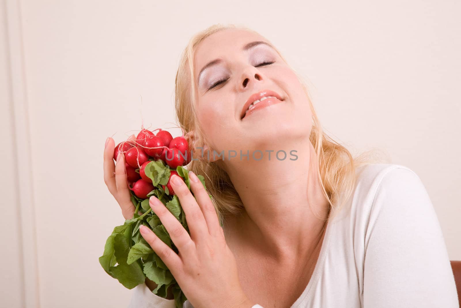 Pretty blond woman caressing a bunch a radish