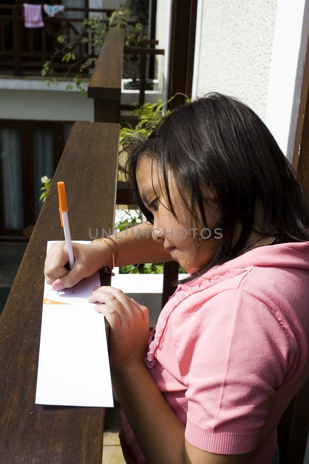 asian little girl writing on the balcony