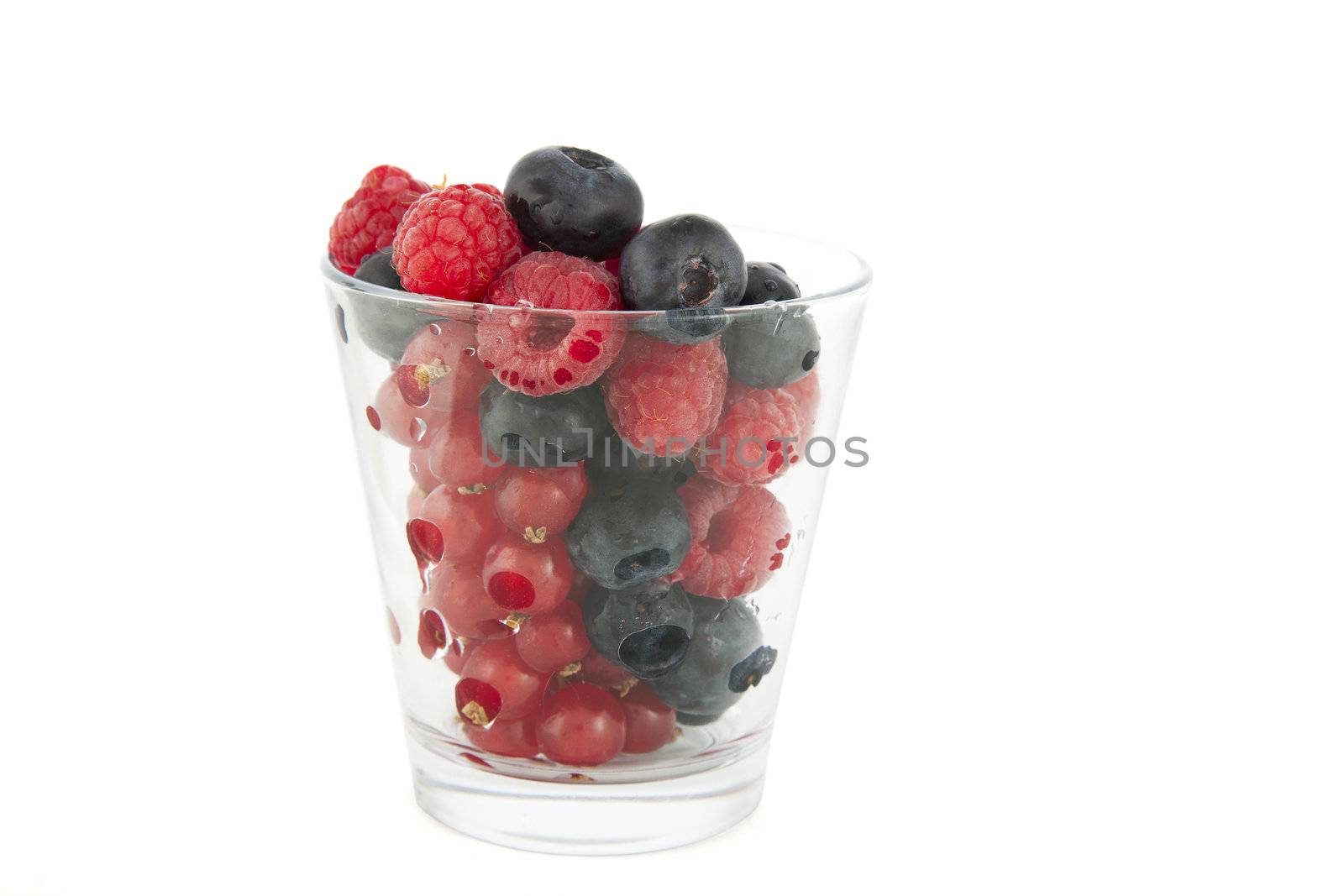 Glass full of fresh blueberries, raspberries and red currants.