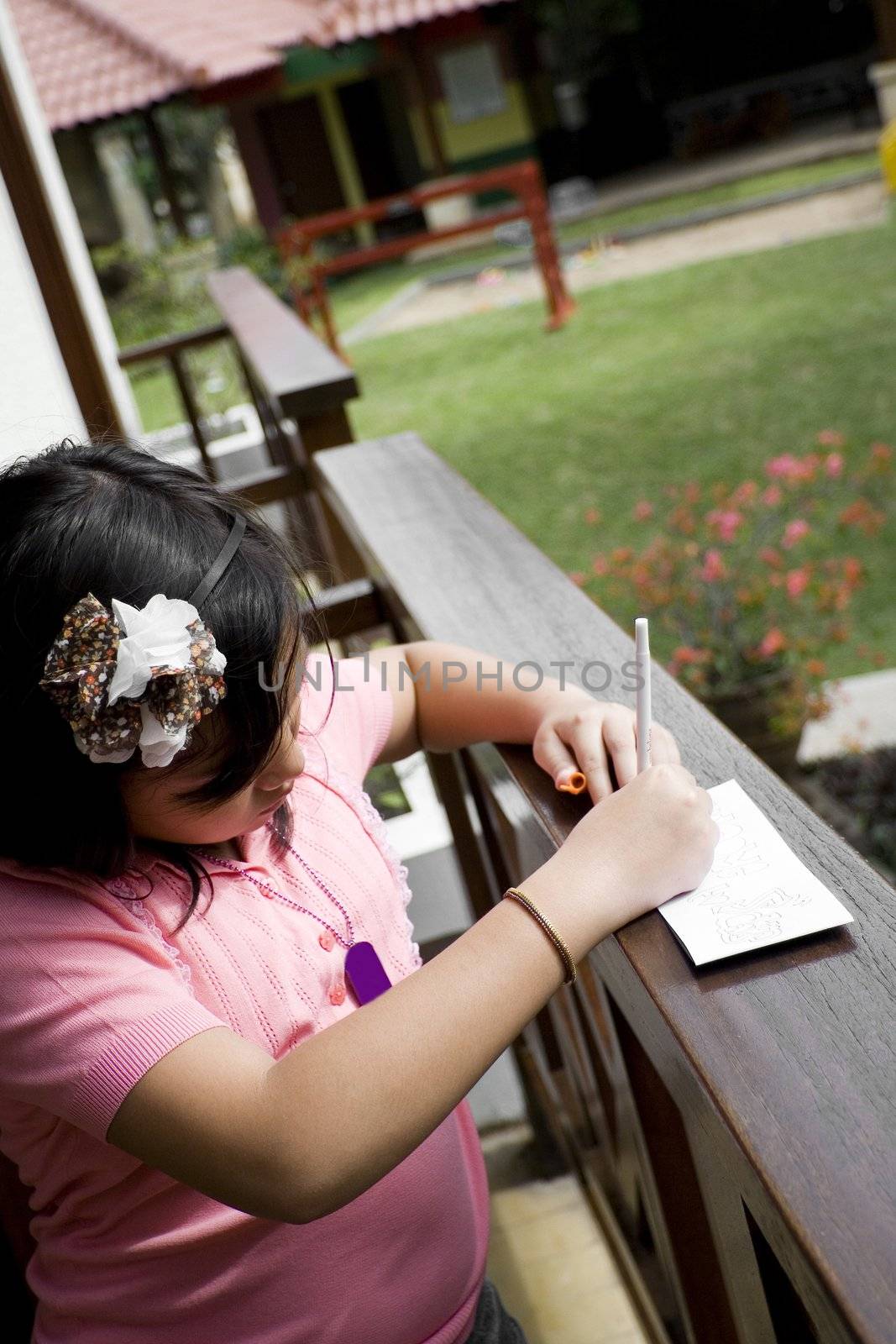 asian little girl writing on the balcony