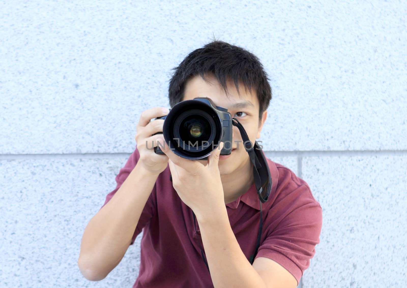 young teenage photographer taking a photo with his DSLR camera.  by cozyta