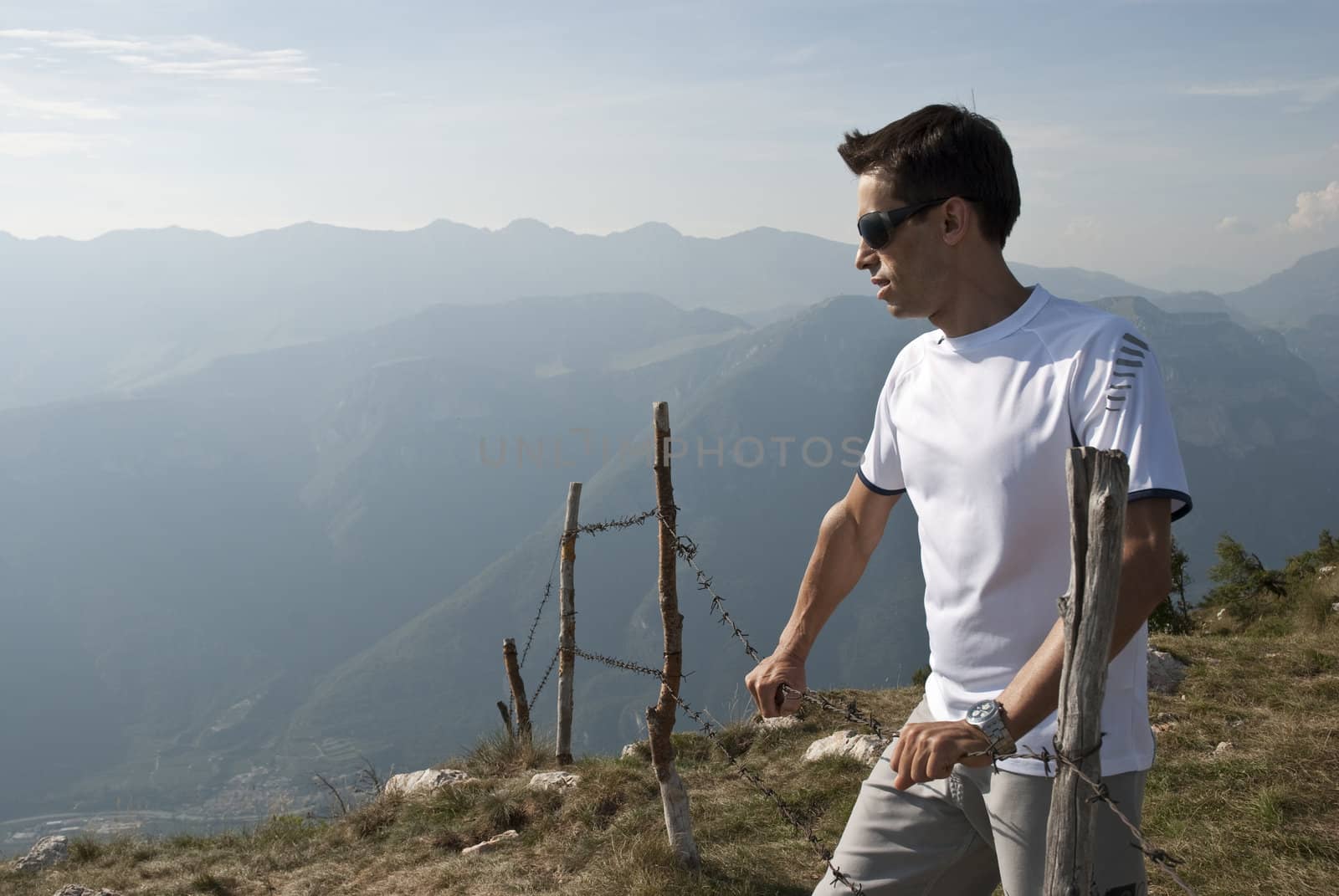 Young man against mountain background in a countryside hiking style scenary.