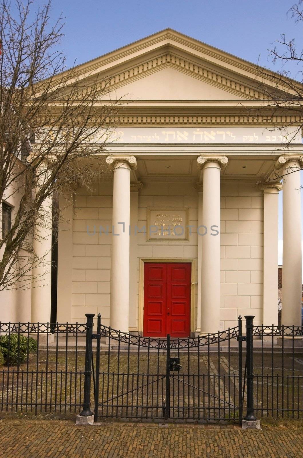 Old synagogue in greek (ionic) style behind a closed metal gate