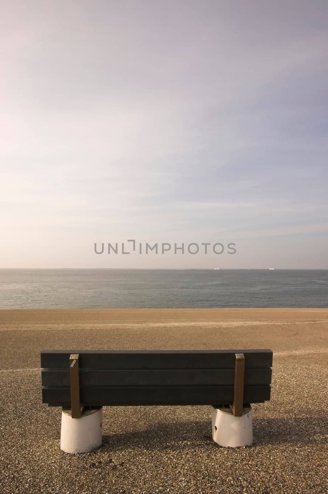 Wooden bench standing at the concrete covered seaside edge in Den Helder in Holland