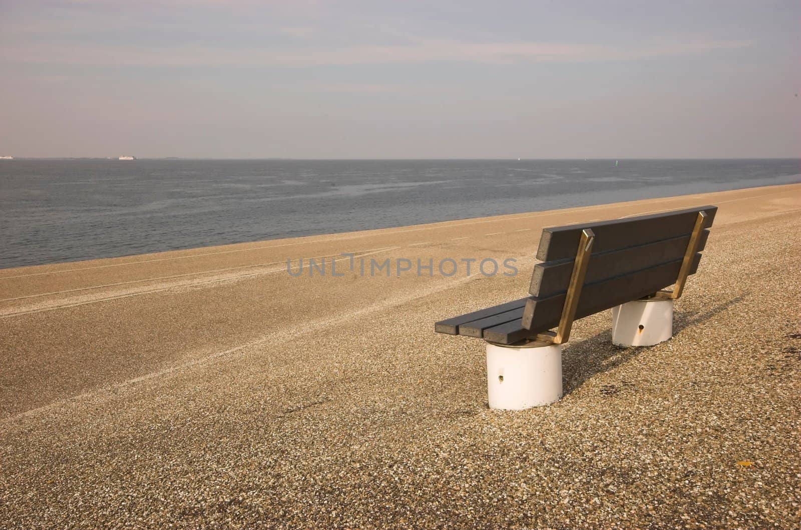 Wooden bench standing at the concrete covered seaside edge in Den Helder in Holland