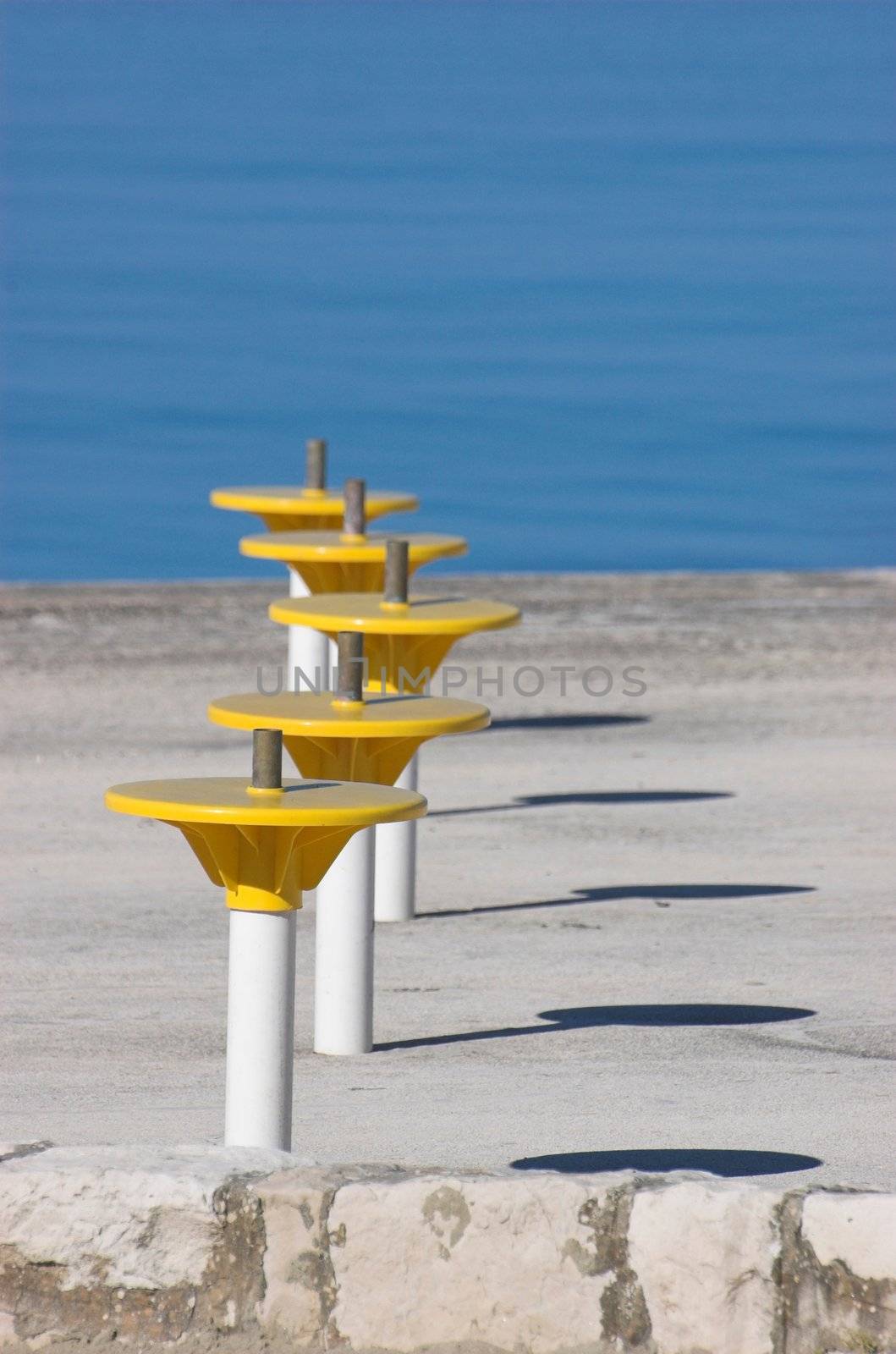 Umbrella holders on a terrace next to a sea
