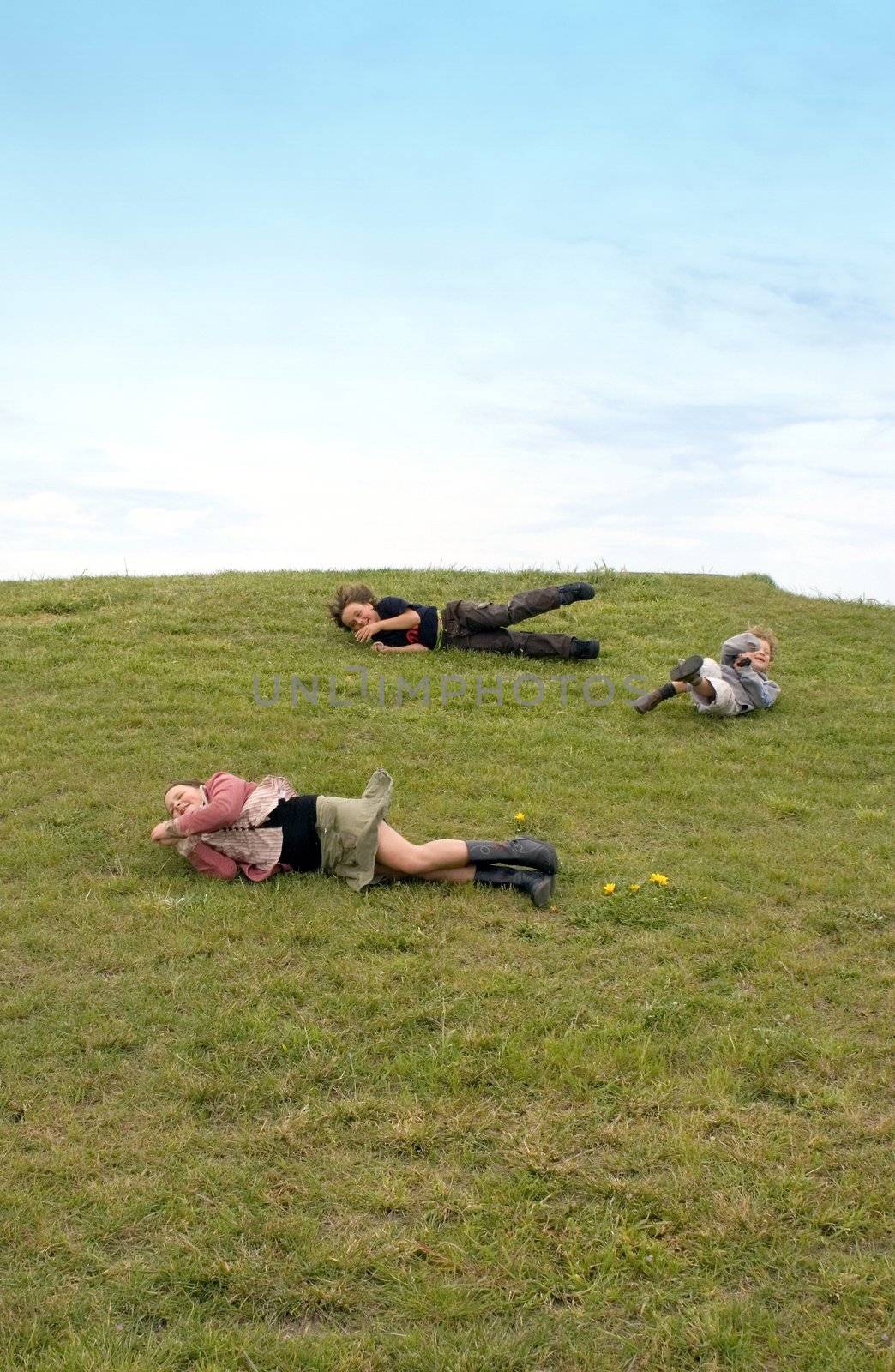 kids having fun rolling down a grassy hill