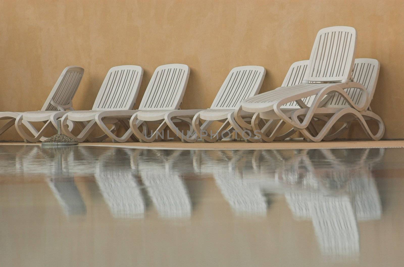 White plastic seats standing on a terrace next to a pool
