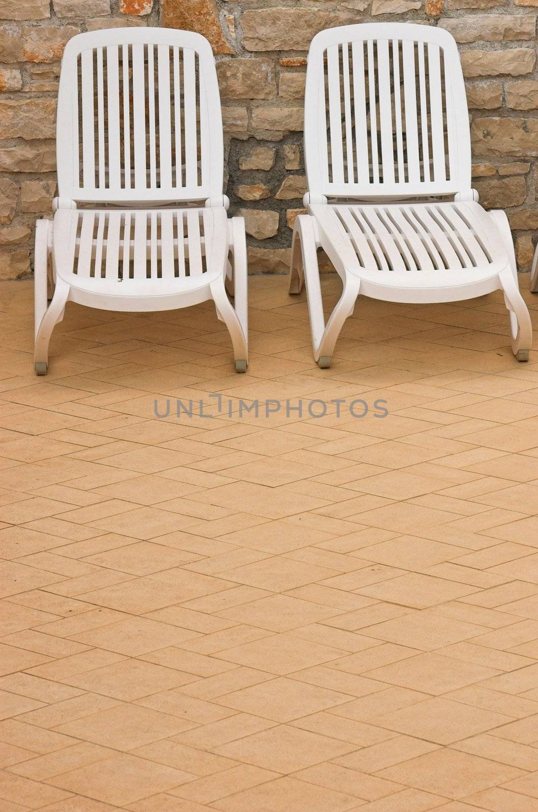 Plastic white chairs standing on a swimming pool terrace