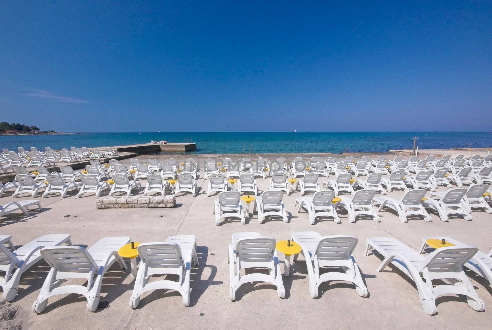 Plastic chairs rowed on a concrete terrace next to sea