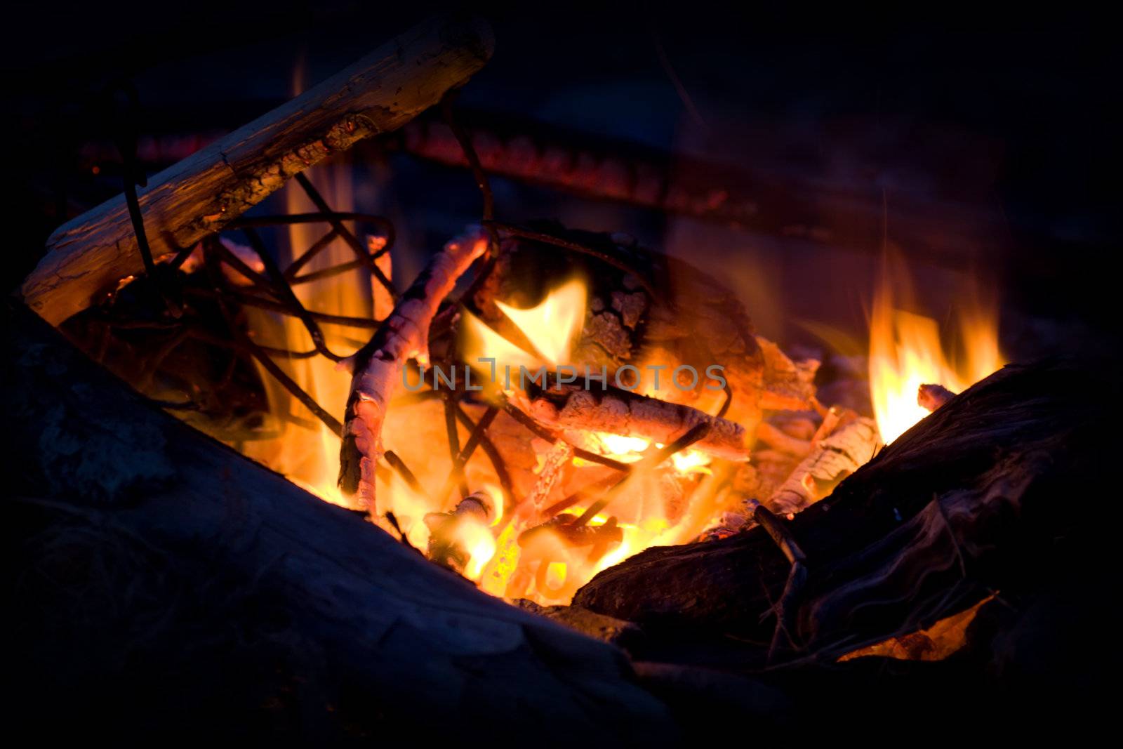 A fire on the beach burns low