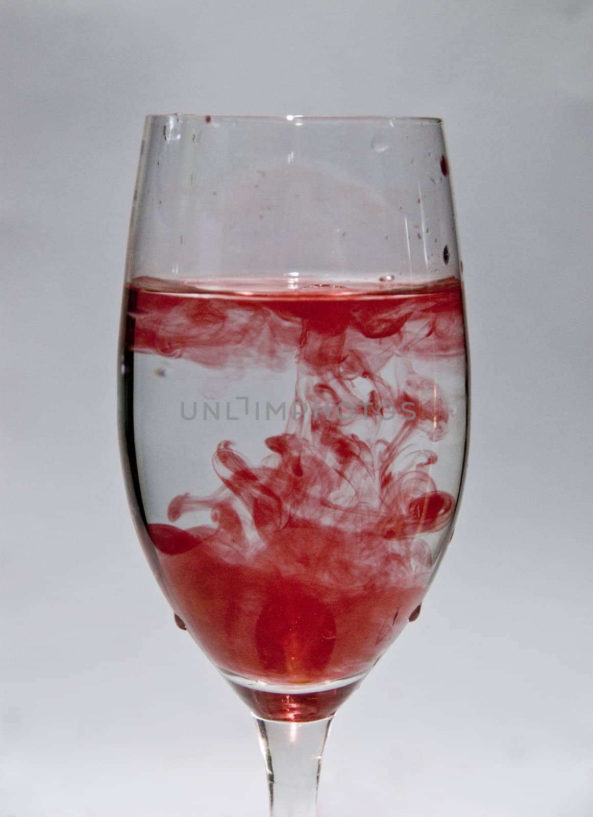 a cup of water with drops of red wine