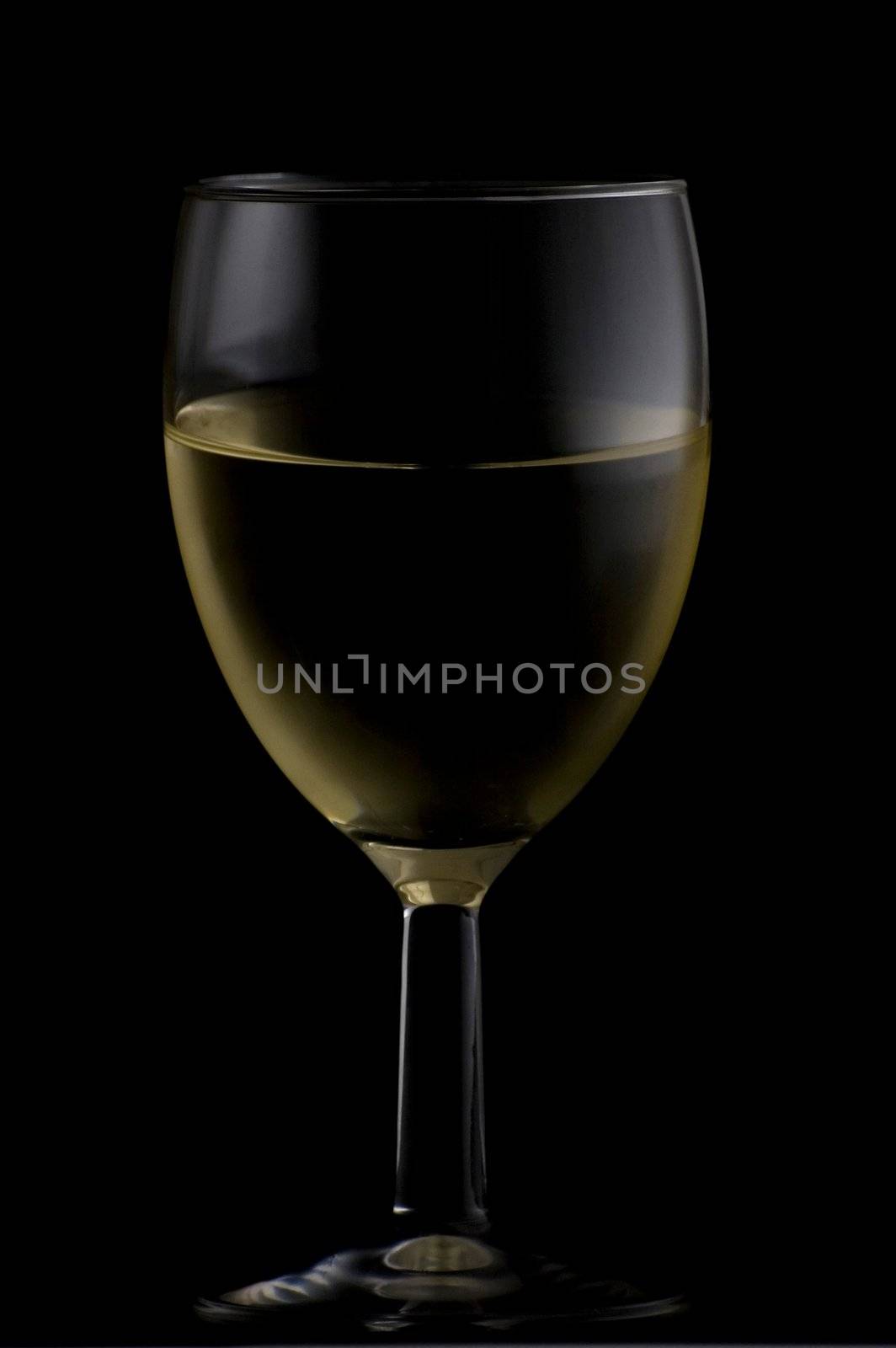 Short wine glass isolated on black filled with white wine