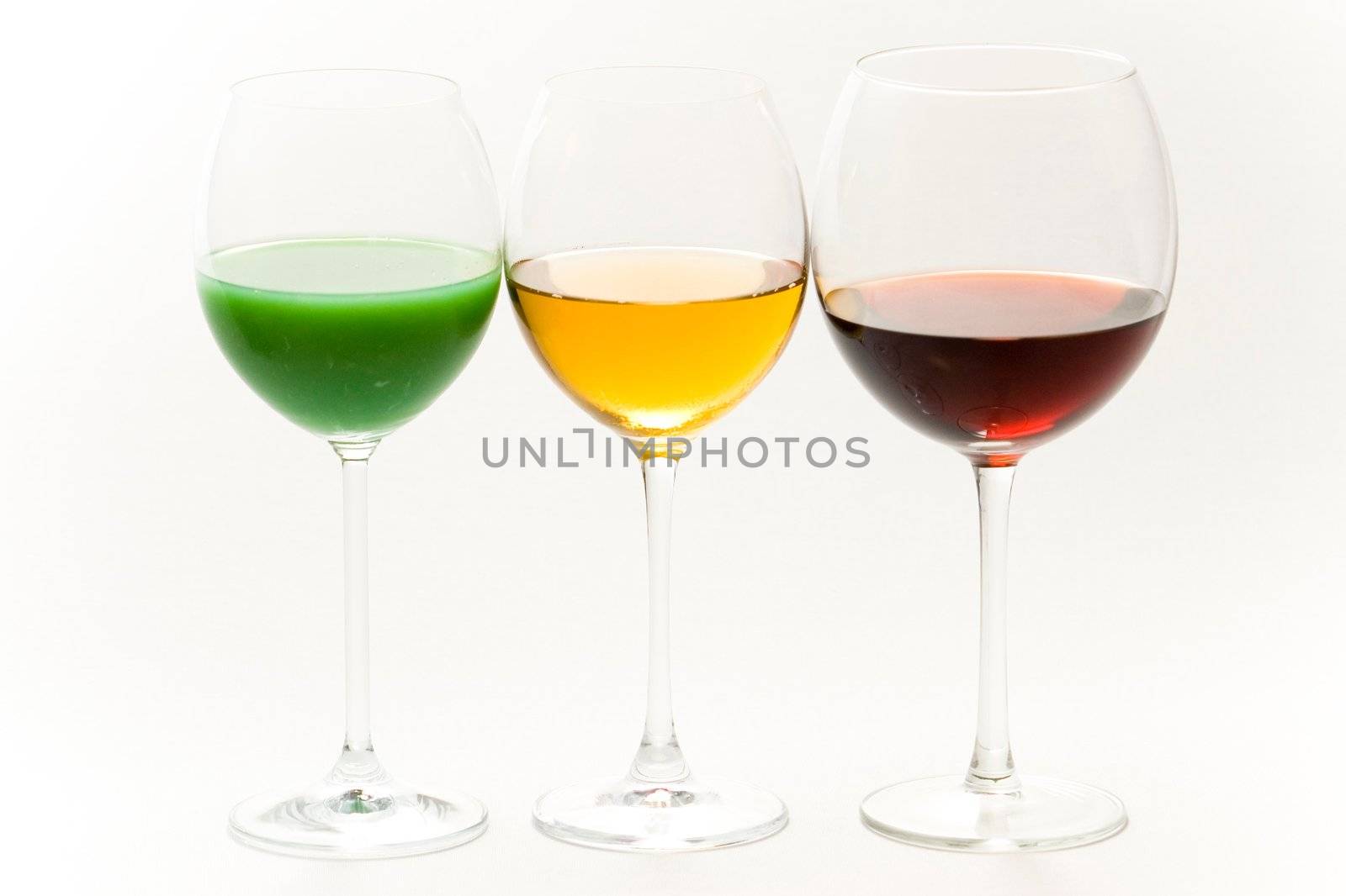 Three tall glasses on white background filled with: white, red wine and green cocktail