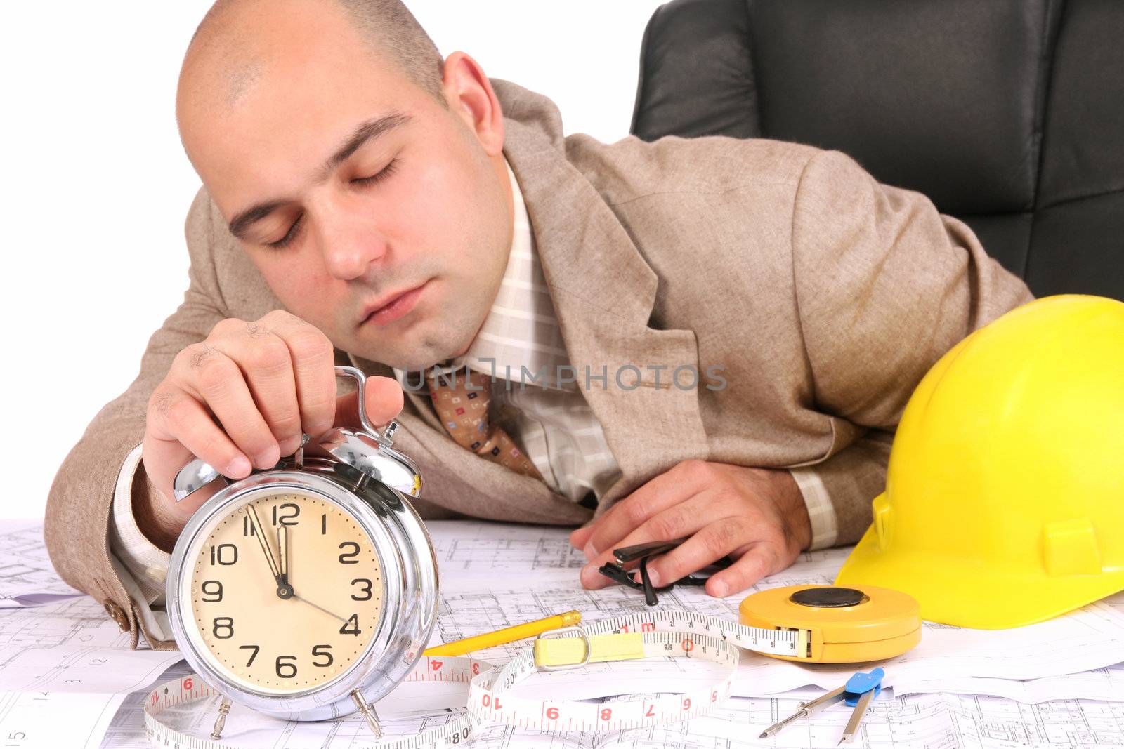 A businessman sleepy with architectural plans at desk