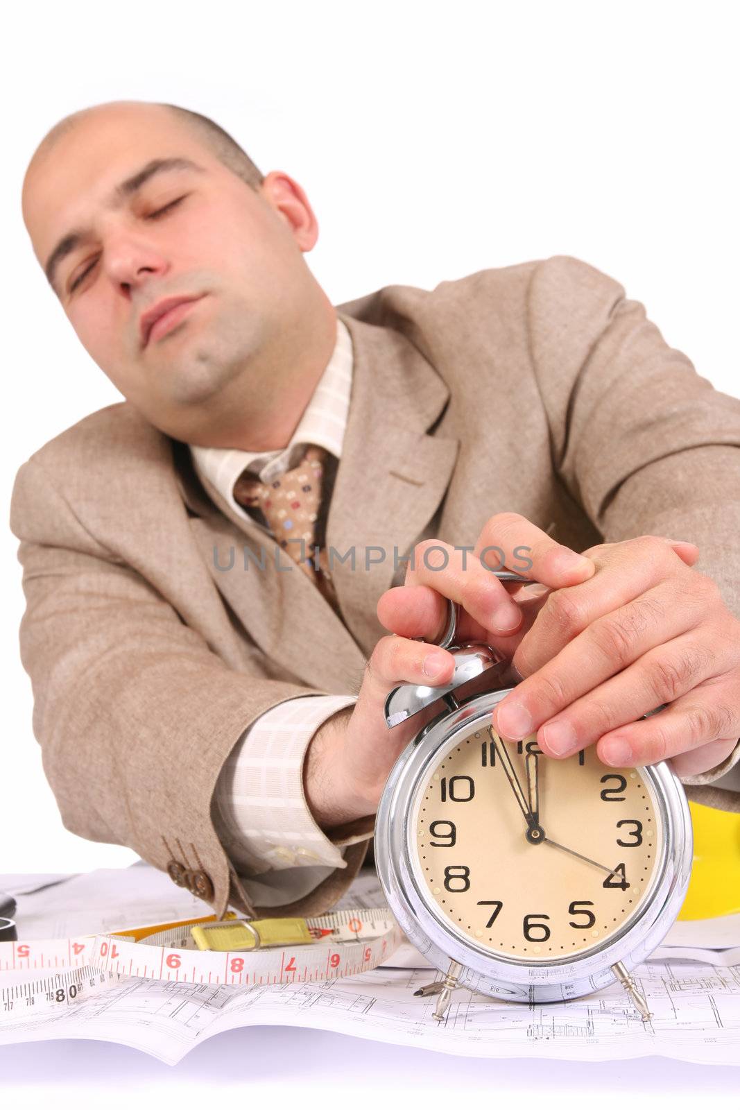 A businessman sleepy with architectural plans at desk