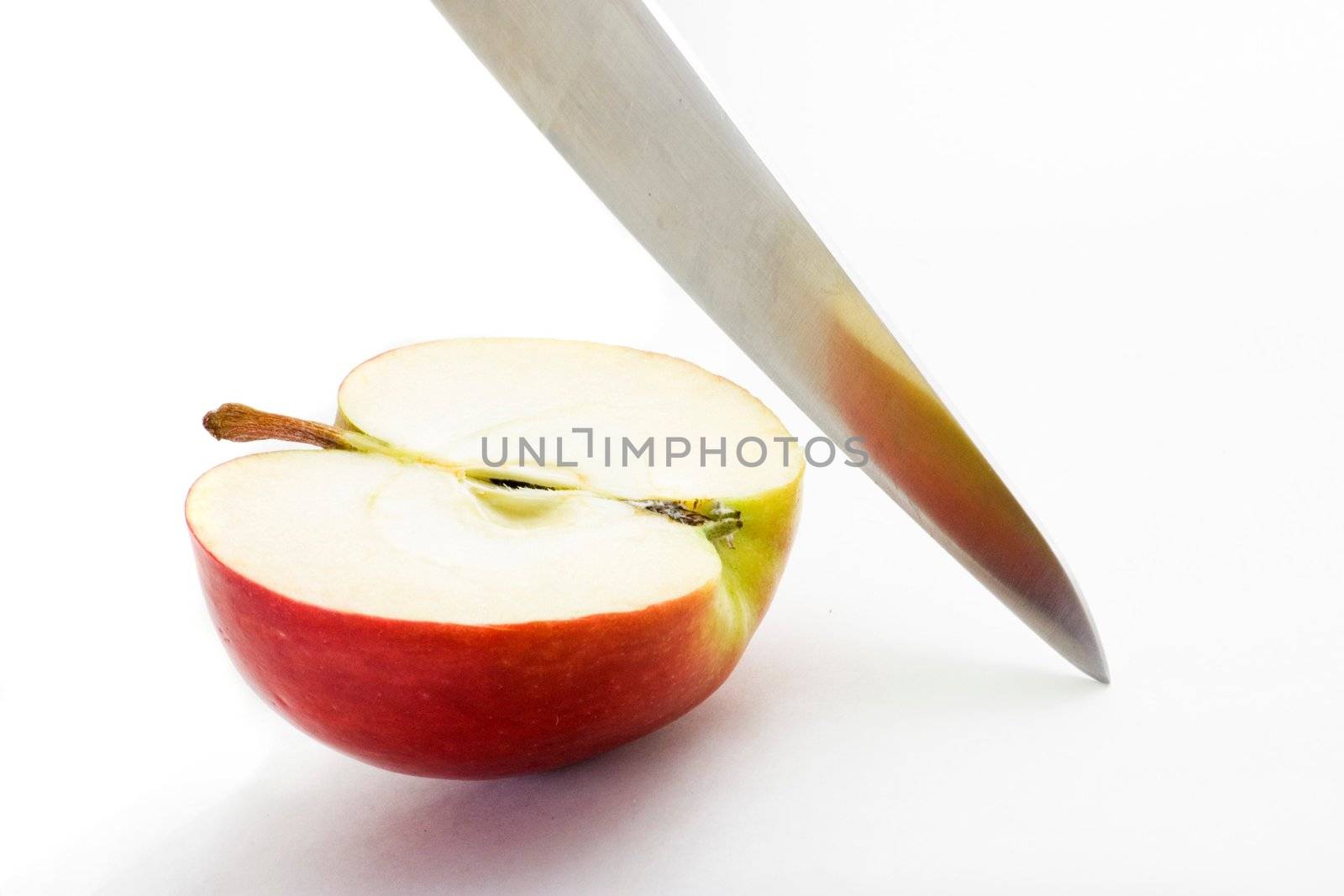 Long bladed kitchen knife cutting through a red apple