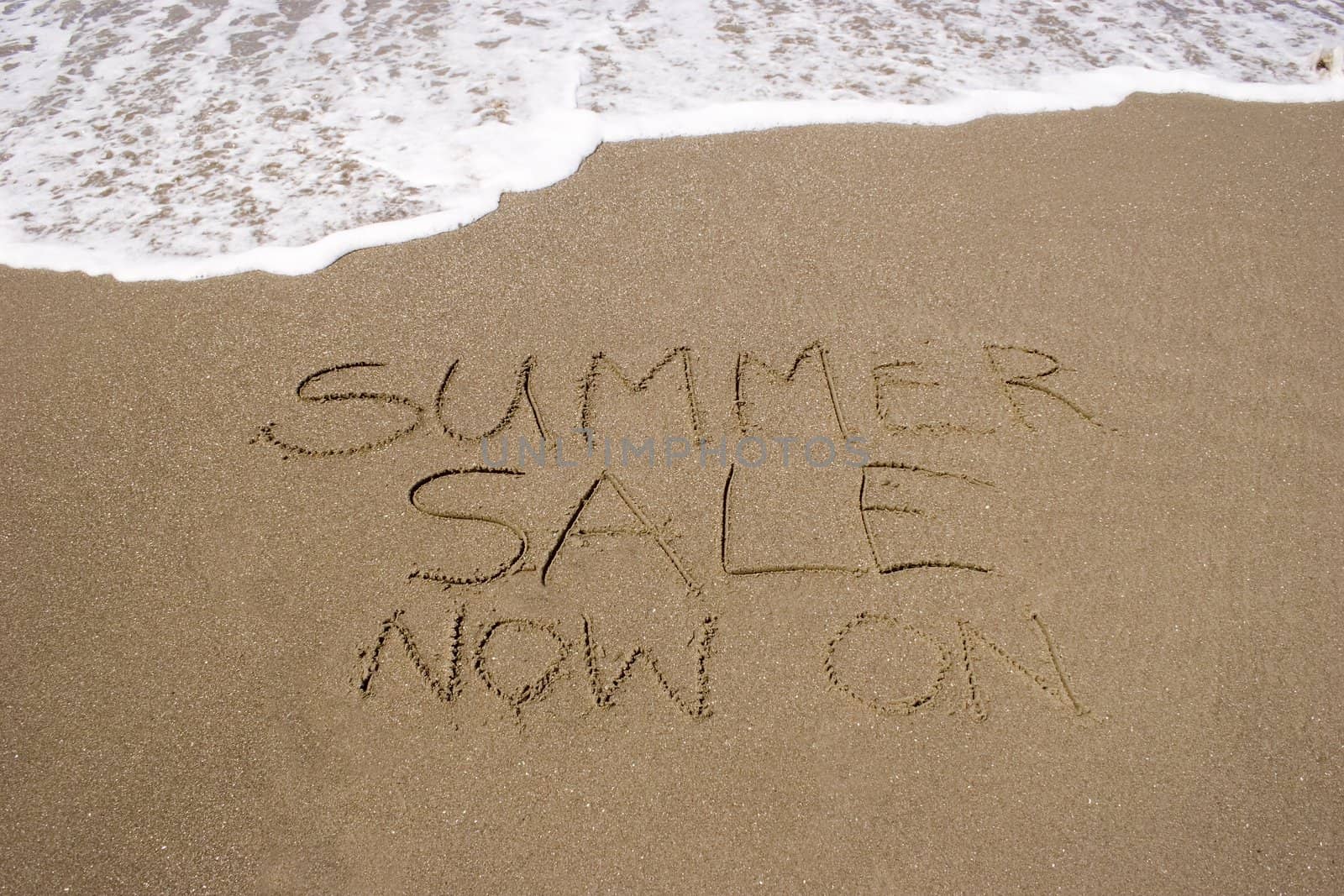 A summer sale written in the sand