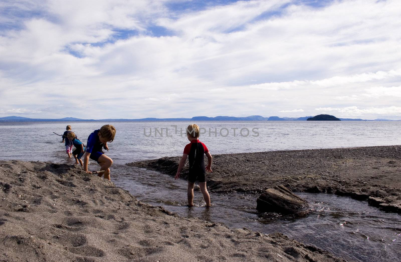 Kids playing by a stream leading into Lake Taupo, New Zealand