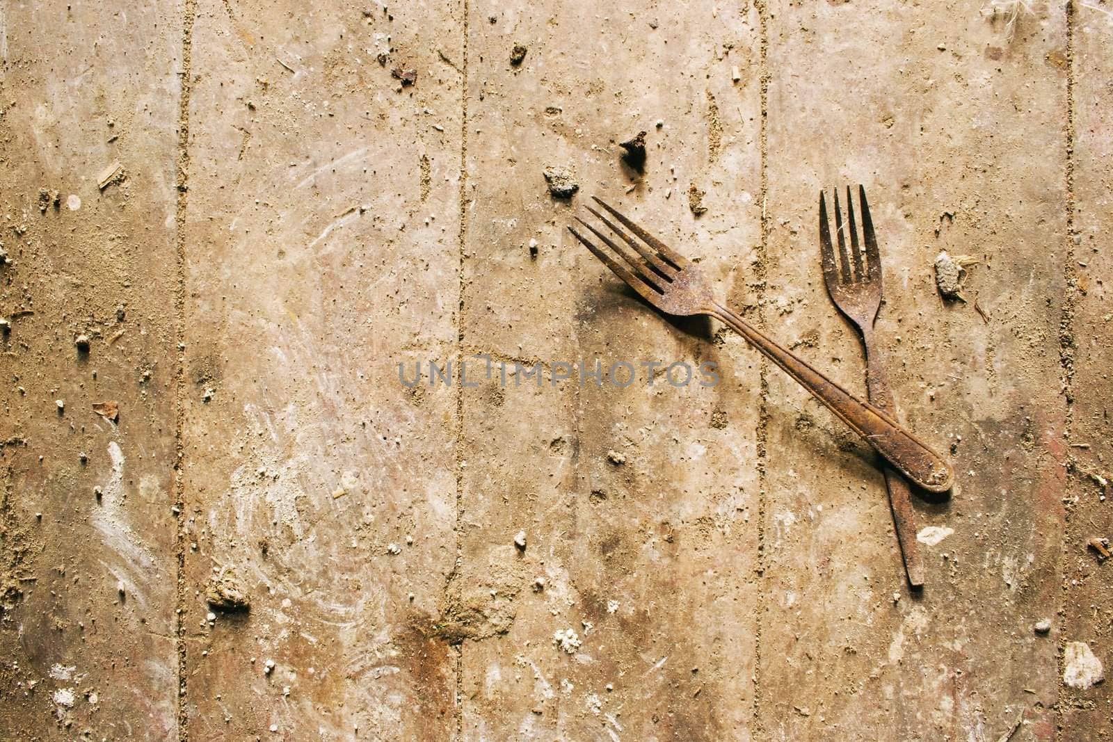 A apir of rusty forks on a dirty wooden floor