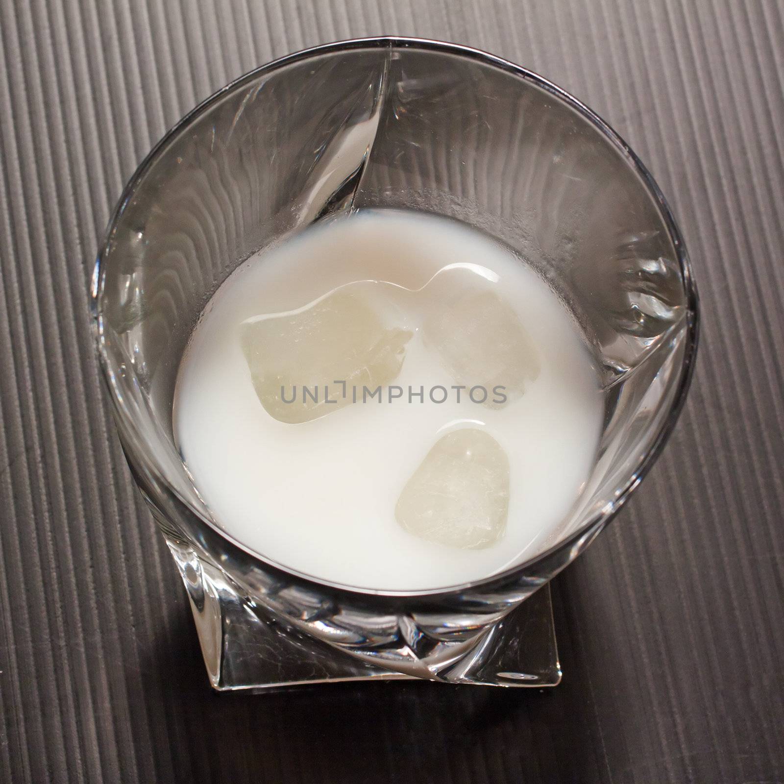 Close up of an elegant glass with white liquor (limoncello cream) with three blocks of ice