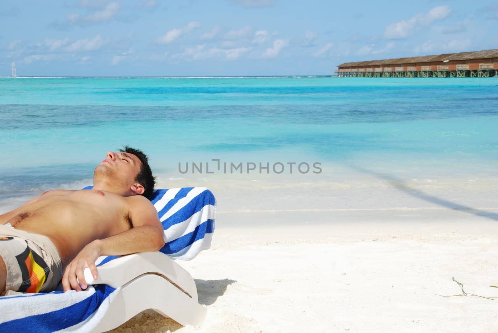 Young man sunbathing in a Maldivian Island beach by luissantos84