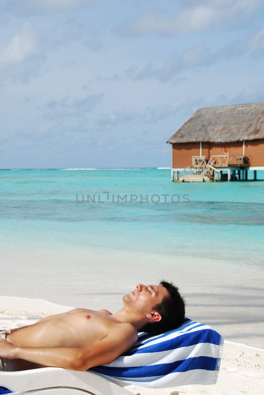 beautiful photo of a handsome man sunbathing at a Maldivian resort (ocean background)