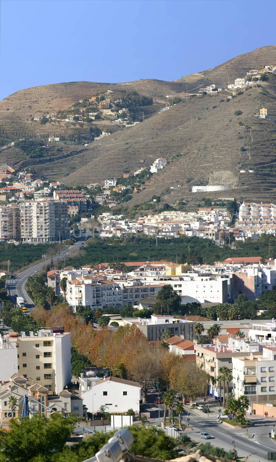 Vertical panorama of a road running through a Spanish town, with mountains in the background