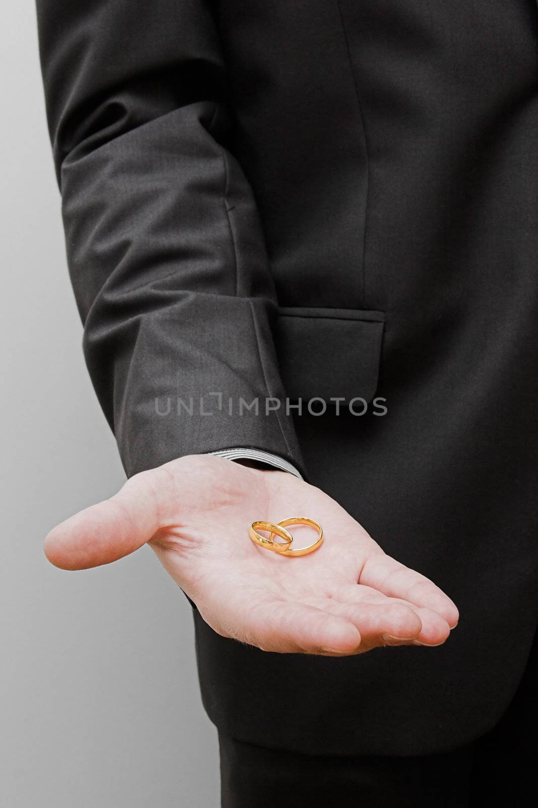 Groom holding a pair of rings on is hand