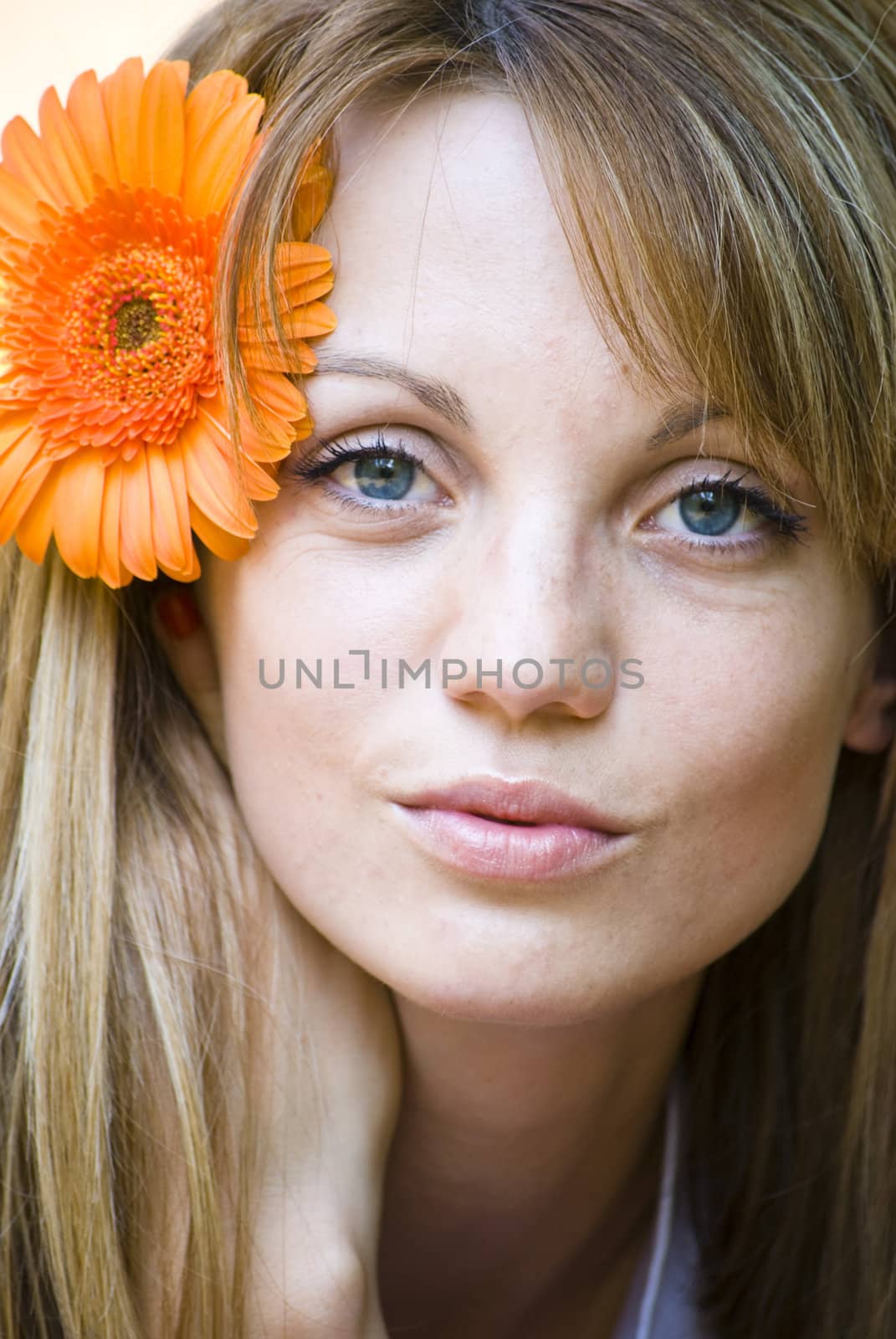portrait of beautiful young blond woman with gerbera flower