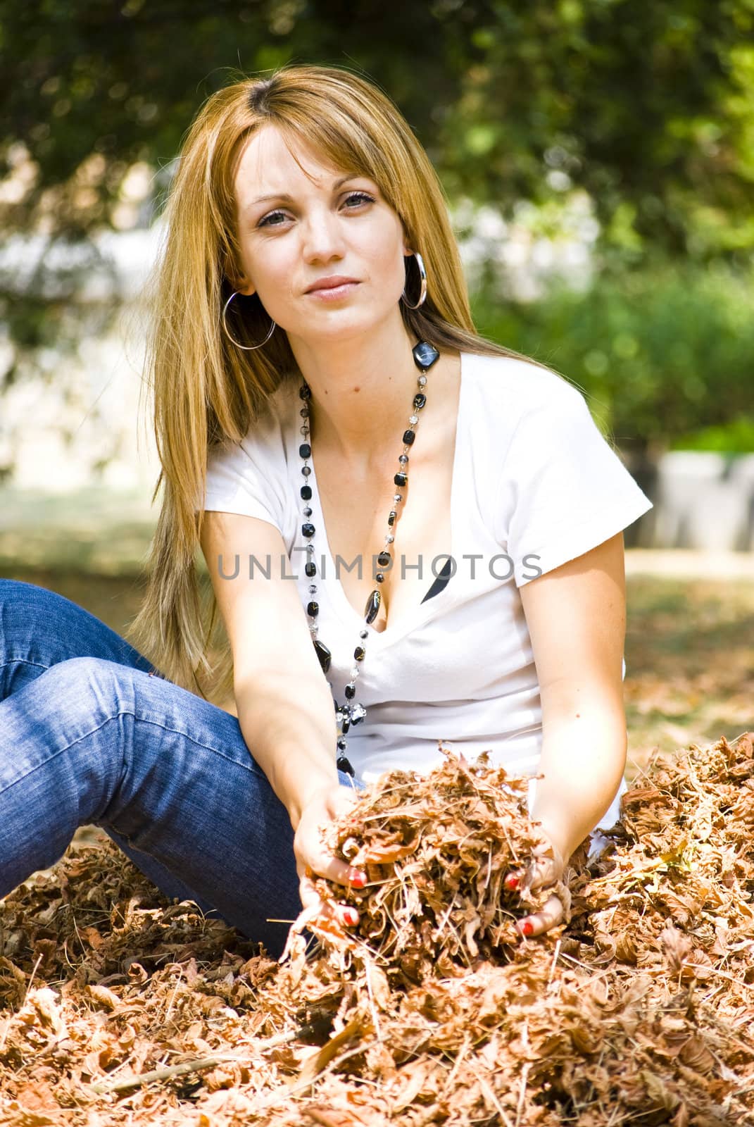 beautiful young model throwing leaves in park