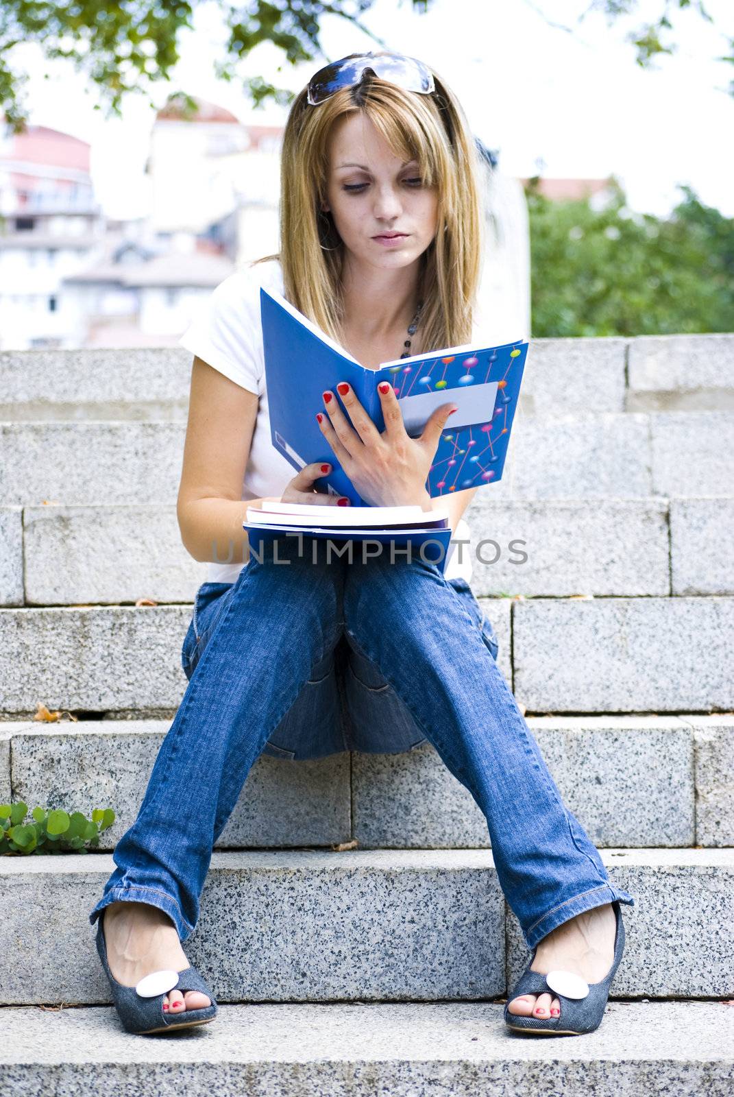 young beautiful woman holding books and reading on stairs