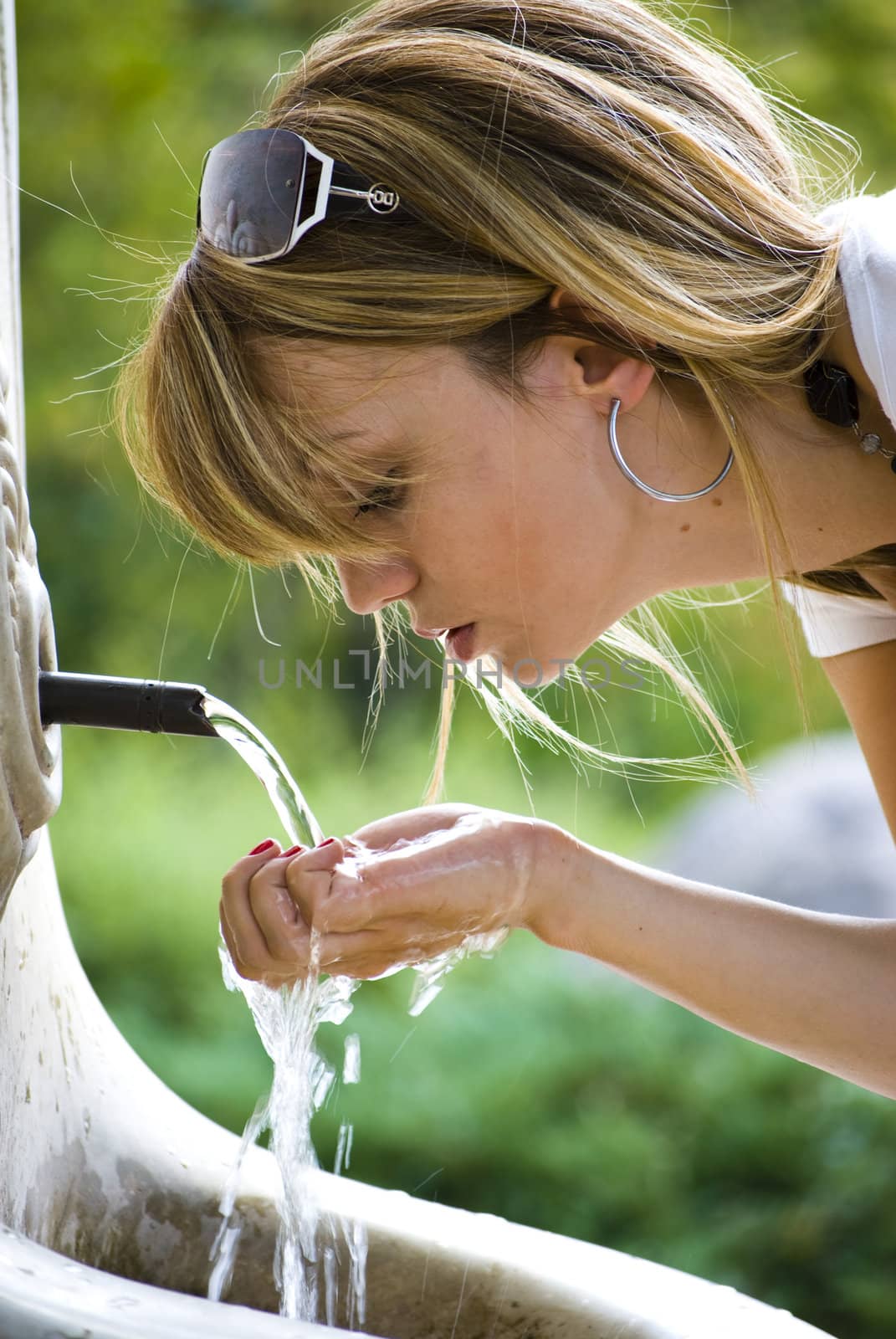 young woman drinking water in park